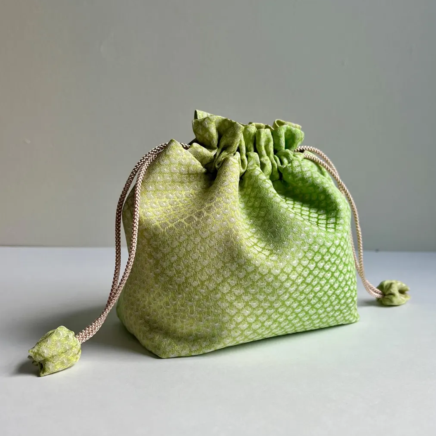 Gradient Light Green Textured Woven Drawstring Bucket Pouch With Ruffled Gathered Top, Fabric Wrapped Cord Toggles And Flat Collapsible Soft Silhouette
