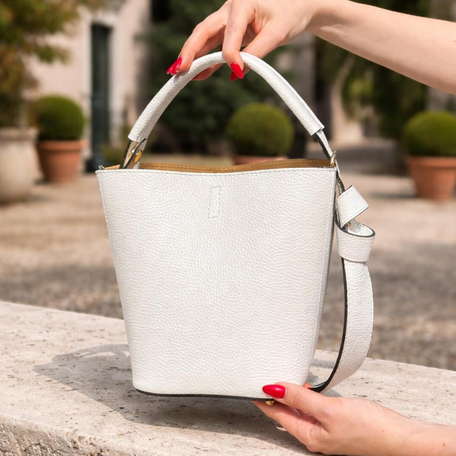Crisp Off-White Pebbled Grain Compact Tapered Bucket Carry With Fixed Curved Top Loop, Decorative Knotted Shoulder Strap And Protective Base Foot Hardware