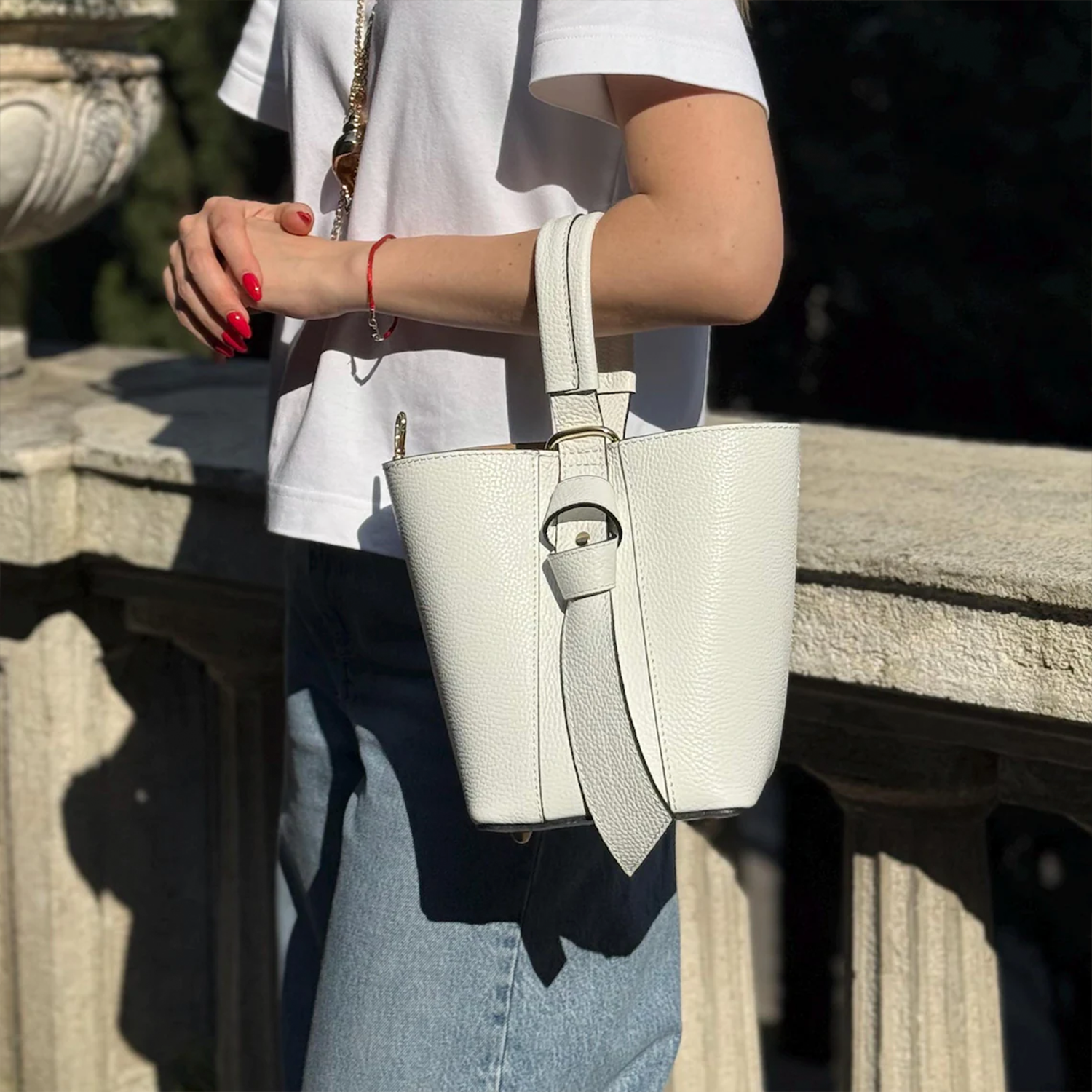 Crisp Off-White Pebbled Grain Compact Tapered Bucket Carry With Fixed Curved Top Loop, Decorative Knotted Shoulder Strap And Protective Base Foot Hardware